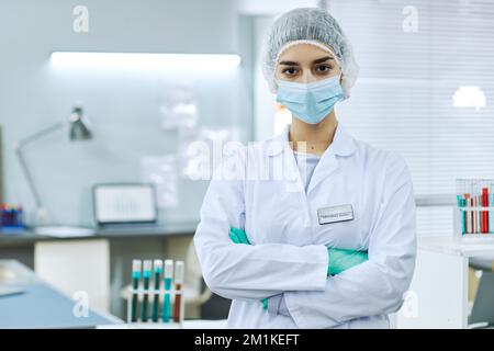 Waist up portrait of young woman wearing lab coat posing in clinic laboratory with arms crossed, copy space Stock Photo