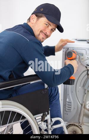 disabled repairman is repairing a washing machine Stock Photo