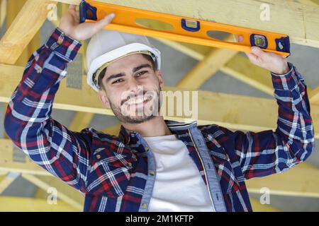male construction worker using spirit level on wooden beam Stock Photo