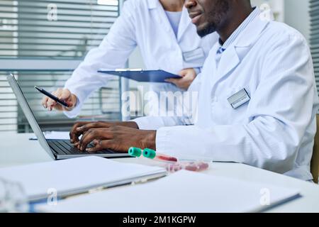 Close up of scientist using laptop while doing research in medical lab, copy space Stock Photo