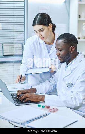 Vertical portrait of two scientists using laptop in medical laboratory Stock Photo