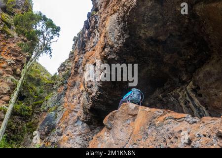 Rear view of a hiker at Mau Mau caves in Chogoria Route, Mount Kenya National Park, Kenya Stock Photo
