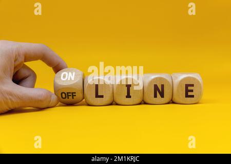 Hand turns a cube and changes the word 'offline' to 'online' Stock Photo