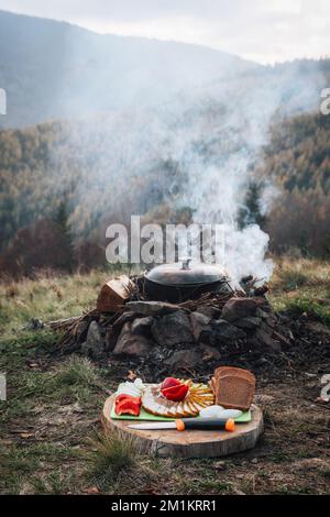 Outdoors Food Concept. Appetizing barbecued steak, sausages and grilled vegetables on a wooden picnic table. Stock Photo
