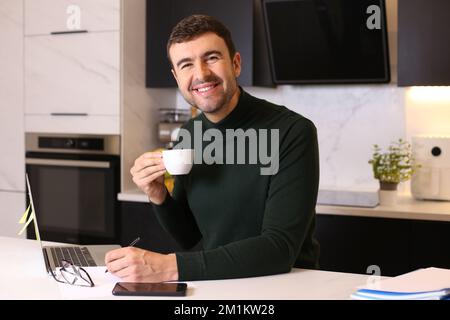 Man drinking a cup of coffee while working from home Stock Photo