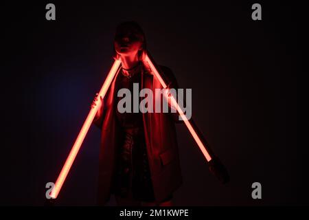 young woman in darkness standing with shining neon lamps on purple and black background,stock image Stock Photo