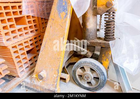 Close up shot on stacked red blocks at the wooden pallet placed on metal, orange manually forklift. Stock Photo