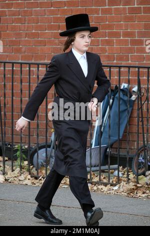 An orthodox Jewish young man with long peyot & black clothing walks briskly at the north end of Lee Avenue in Brooklyn, New York City. Stock Photo