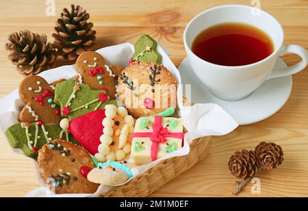 Closeup a Basket of Christmas Cookies and a Cup of Hot Tea on Wooden Table Stock Photo