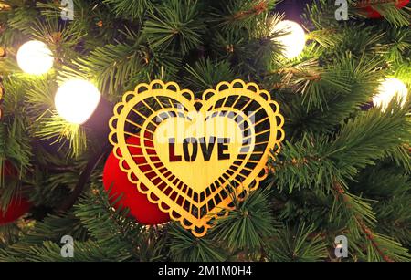 Closeup of Heart Shaped Ornament with the Text LOVE Hanged on the Christmas Tree Stock Photo