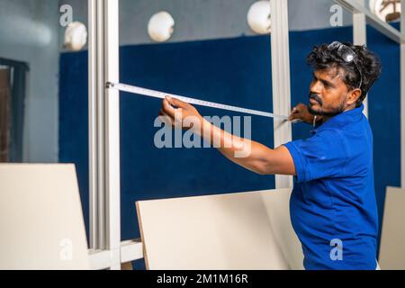 plumber busy working by measusing tape and fixing wood at workplace - concept of blue collar jobs, craftman and professional occupation. Stock Photo