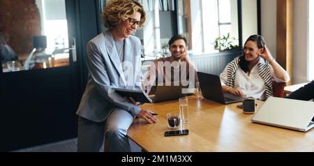 Successful business people having a meeting together. Happy business team discussing a project with their manager. Group of professionals enjoying wor Stock Photo