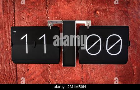 Flip black clock with eleven o'clock time on panel closeup Stock Photo