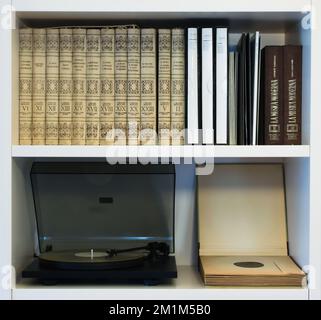 Modern record player spinning a recent vinyl record. Shown in a shelf together with a collection of old classical music records and modern vinyls. Stock Photo