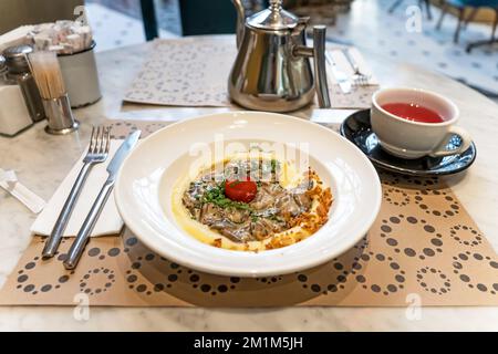 Braised beef, beef stroganoff with gravy on mashed potatoes on a table in a restaurant. Close-up Stock Photo