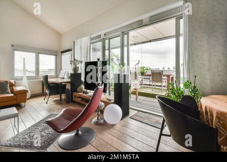 a living room with wood flooring and large sliding glass doors that open onto the balcony overlooking out to the ocean Stock Photo