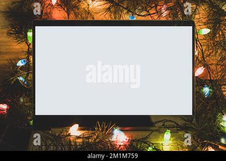 Computer laptop with blank screen in christmas tree. winter backgrounds. copy space for text and design. blank white screen on the laptop. Stock Photo