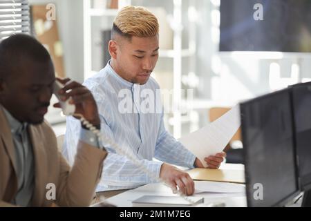 Portrait of young Asian man working with documents in surveillance center Stock Photo