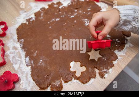 Child making Christmas cookies from Gingerbread dough and cookie cutters Stock Photo