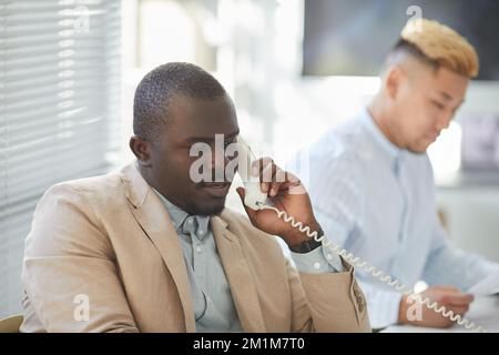 Portrait of black man speaking on phone while advising customer in call center Stock Photo