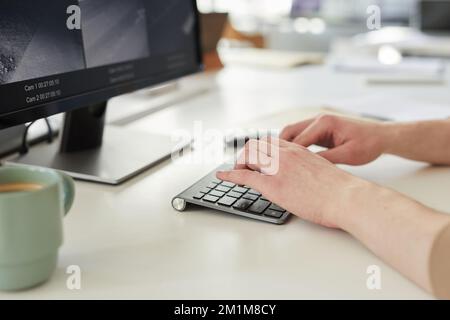 Close up of young woman typing on keyboard while working with surveillance footage in security center Stock Photo