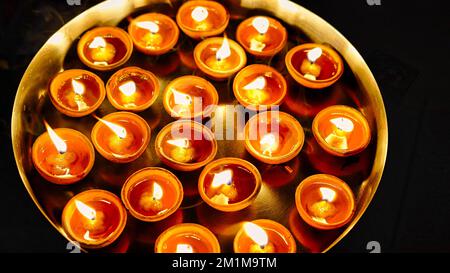 Many Diya or traditional clay lamps on Diwali festival. A girl hand holding oil lamps plate in hand during deepavali festival. Indian Hindu religious Stock Photo