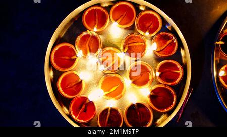 Many Diya or traditional clay lamps on Diwali festival. A girl hand holding oil lamps plate in hand during deepavali festival. Indian Hindu religious Stock Photo