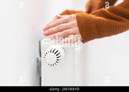 hand adjusting radiator temperature using thermostat. Home with central heating. Stock Photo