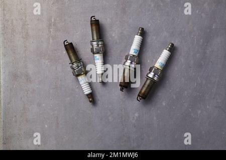 four used car spark plugs that are dirty and time to be replaced Stock Photo