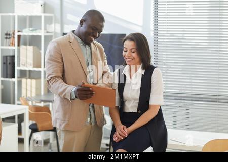 Portrait of two smiling business people looking at digital tablet in classic office interior, copy space Stock Photo