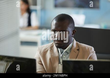 Portrait of focused black man looking at computer screen while working in office Stock Photo