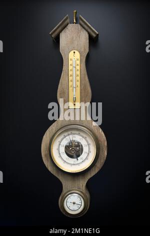 Old wall barometer with built-in hygrometer and thermometer. Black background Stock Photo