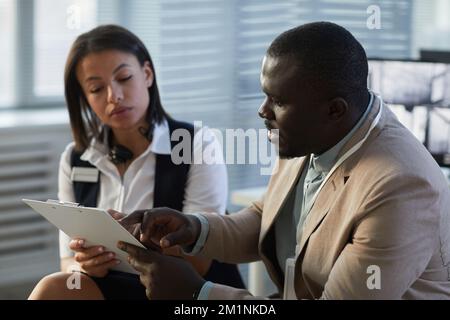 Portrait of black businessman working with young woman while reviewing documents in office Stock Photo