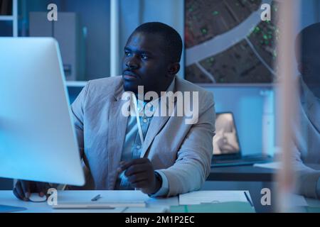 Portrait of black man working in security center and using computer, blue tone scene Stock Photo