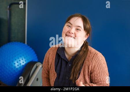 a girl with down syndrome is sitting smiling. Stock Photo