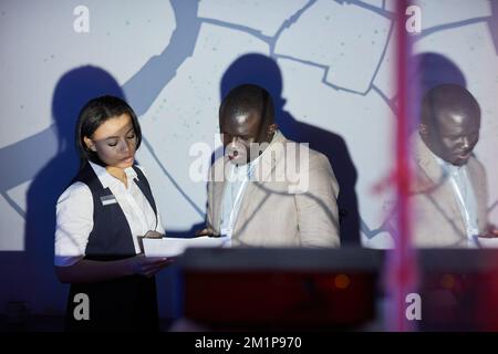 Waist up portrait of two business people looking at documents in security and control center with city map on projector screen Stock Photo
