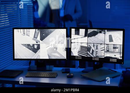 Background image of computer screens with surveillance camera footage in dark room Stock Photo