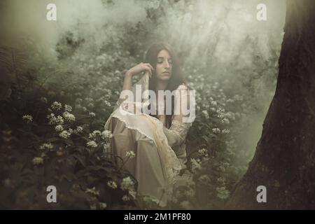 Victorian dressed woman in a misty forest Stock Photo
