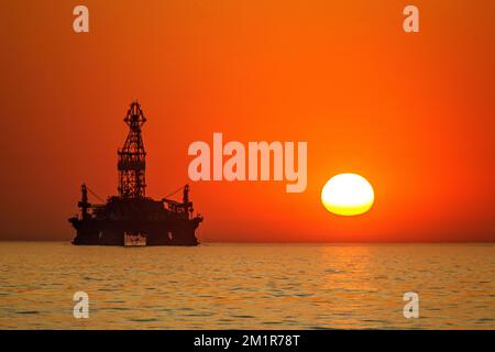The Drilling Platform 'West Eclipse' awaiting maintenance outside Walvis Bay in an orange sunset. Stock Photo