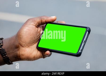 black african hand holding and using blank screen mobile phone horizontally Stock Photo