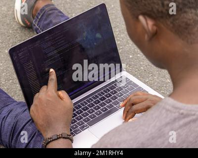 Hand portrait of african web developer pointing finger at line of computer code Stock Photo