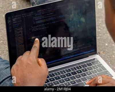 Hand portrait of african web developer pointing finger at line of computer code Stock Photo