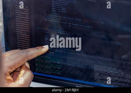 Hand portrait of african web developer pointing finger at line of computer code Stock Photo