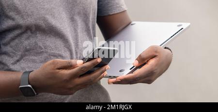 African man hand reading text message on mobile phone while in urban setting. Stock Photo