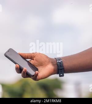 Hand of an African farmer man holding a black smartphone. Stock Photo