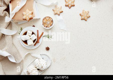 Christmas aesthetic seasonal background with cup of hot drink, white marshmallows, homemade snowflakes cookies, cinnamon sticks and books at cozy home Stock Photo