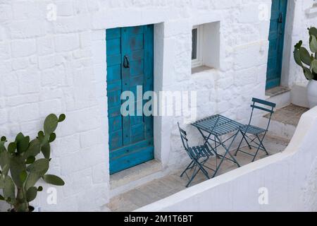 Whitewashed house with table and chairs on balcony and blue door, Ostuni, Brindisi province, Puglia, Italy, Europe Stock Photo