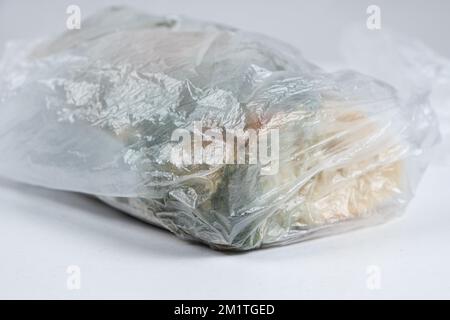 Bread with mold in a plastic bag on a white background, close-up. Stock Photo