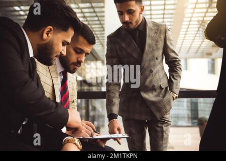 An international team of successful young business men in suits at a meeting are discussing the implementation of business plans together. Stock Photo