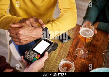 Customer making wireless or contactless payment using smartwatch in a bar Stock Photo